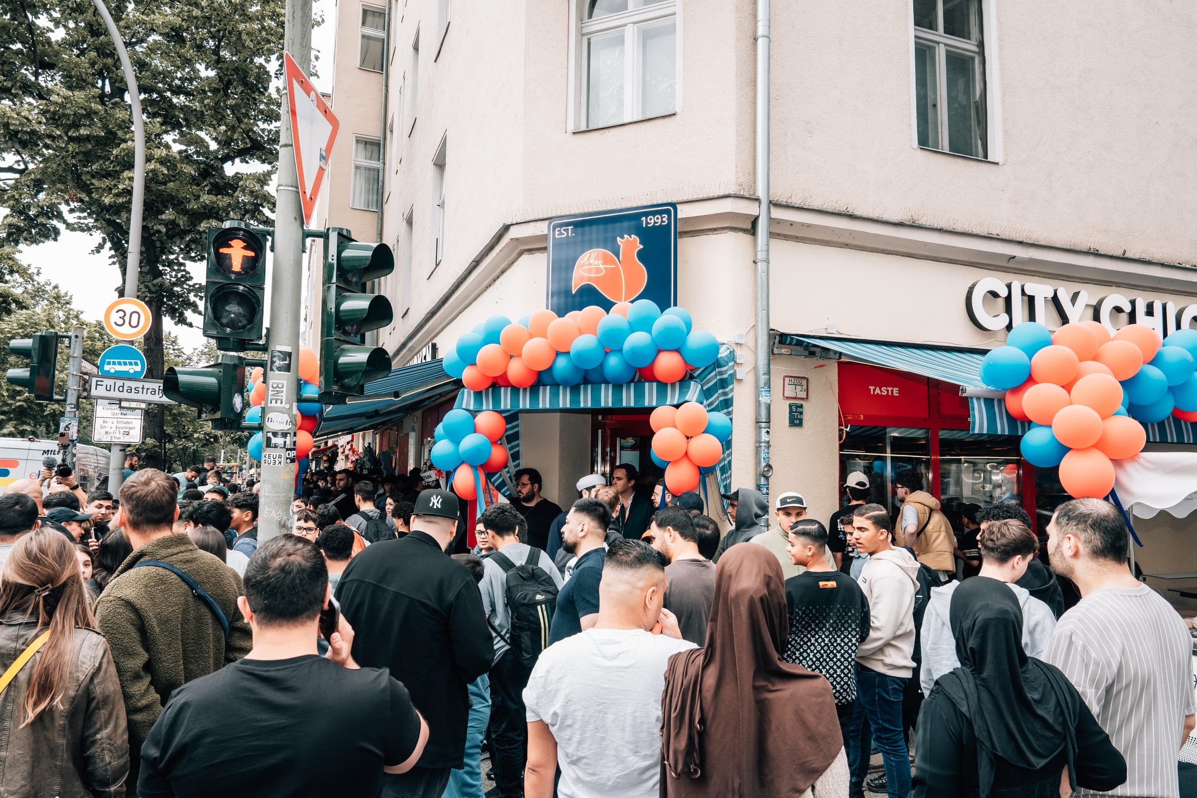 Menschenmenge mit Luftballons bei der Neueröffnung von Nhas City Chicken an der Sonnenallee Ecke Fuldastraße in Berlin-Neukölln