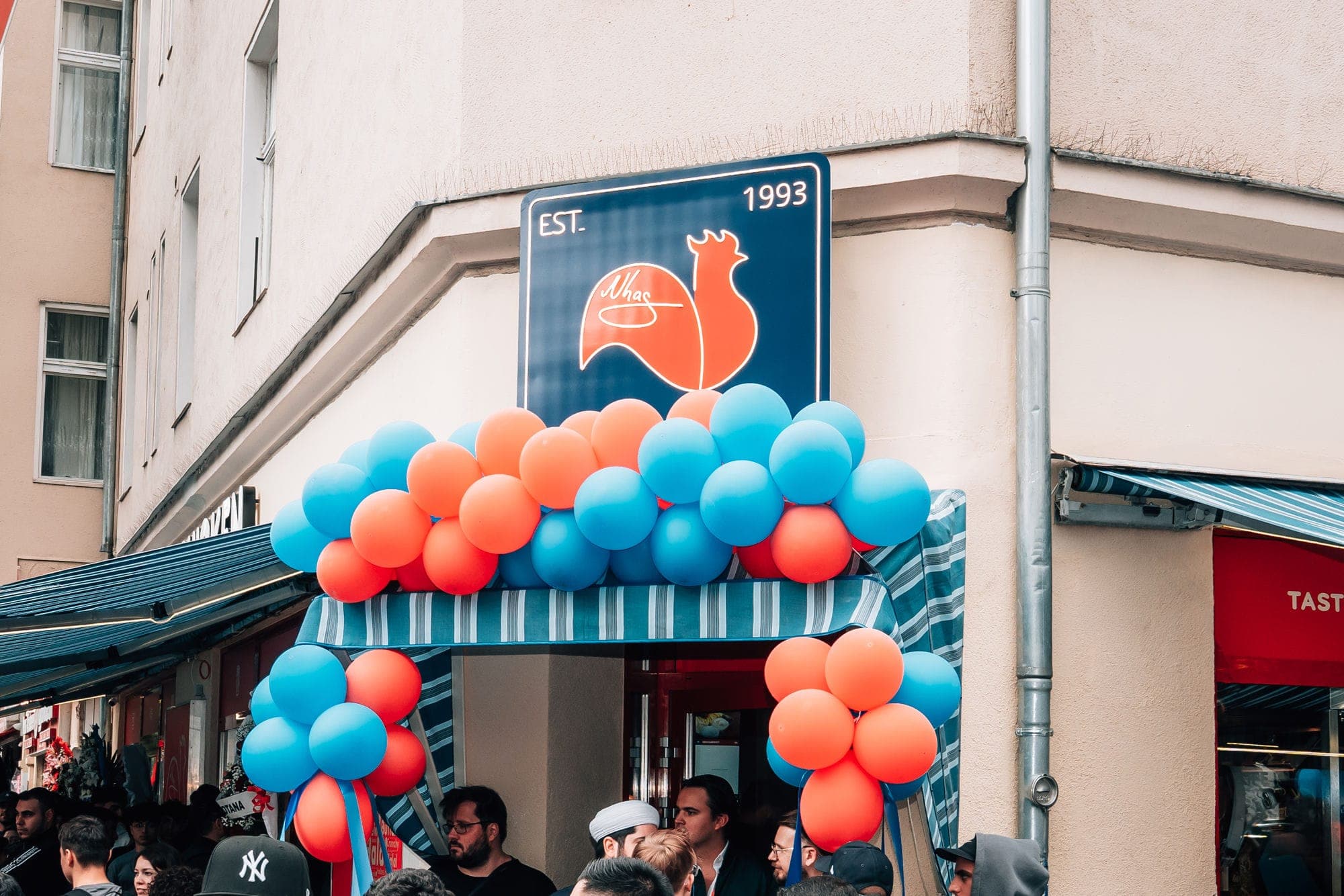 Eröffnung von Nhas City Chicken mit Luftballons unter dem EST.-1993-Schild